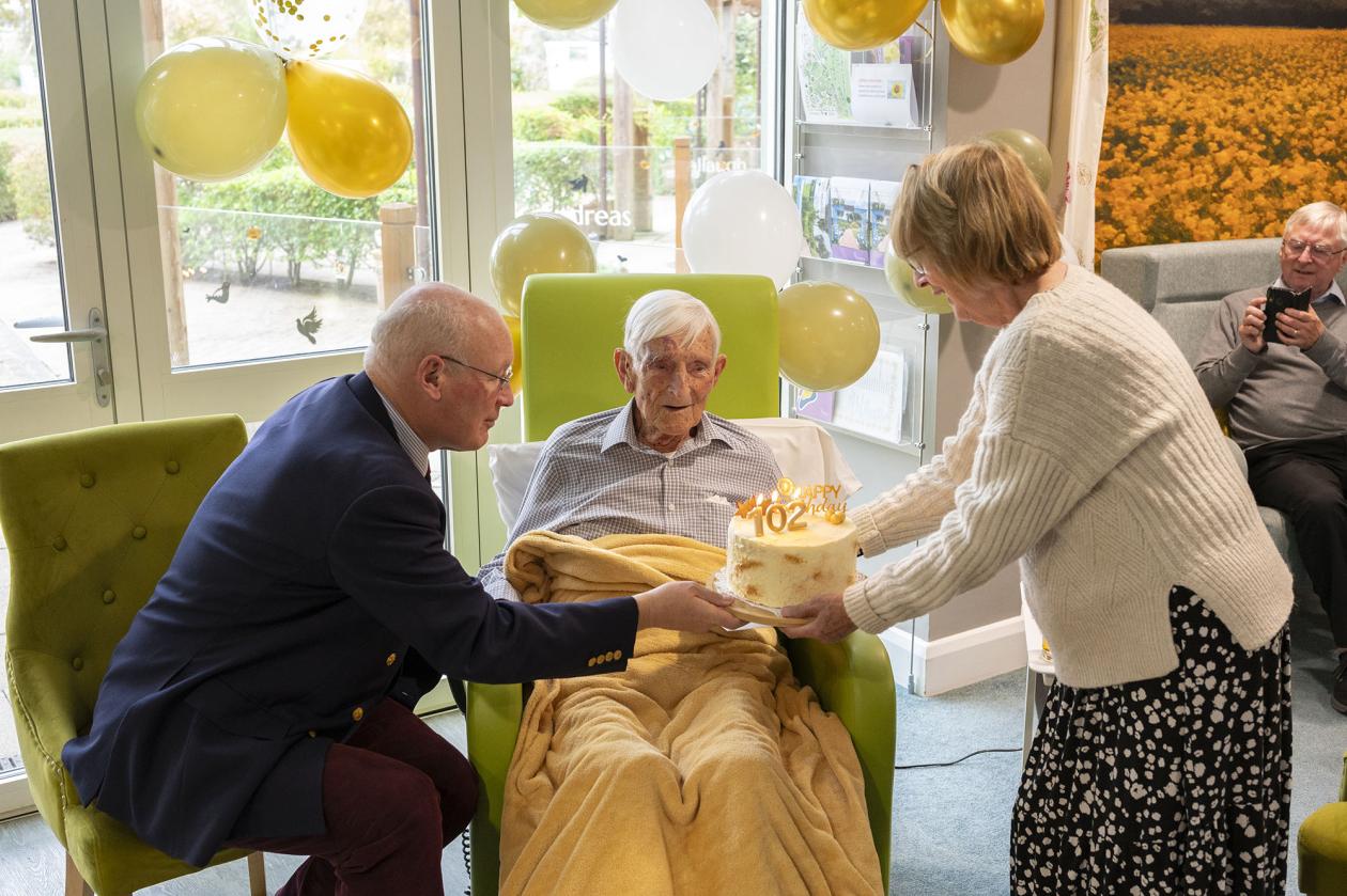 Patient receiving a cake on his 102nd birthday
