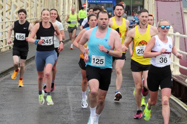 Runners jogging over Ramsey swing bridge