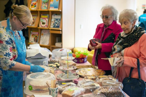 Ladies gather around a table at a cake sale