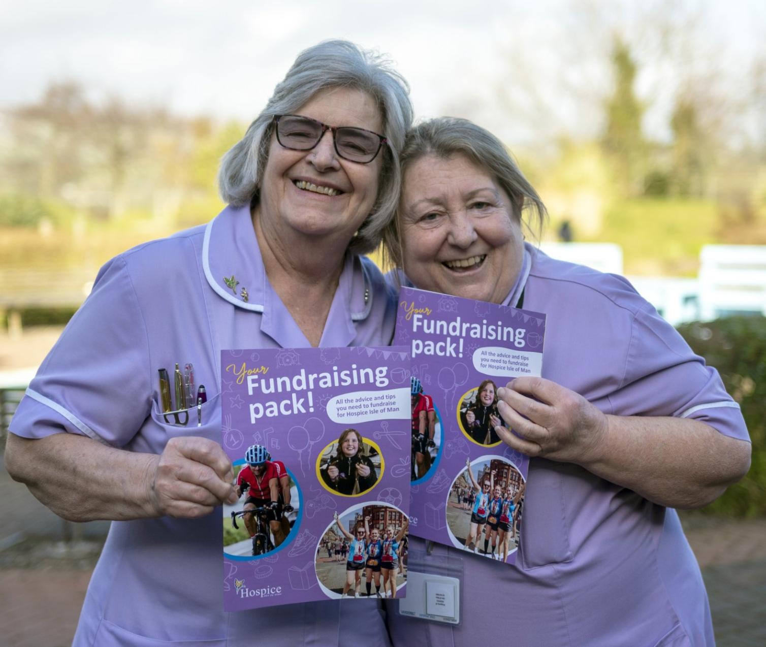 Two nurses holding up a fundraising pack to the camera