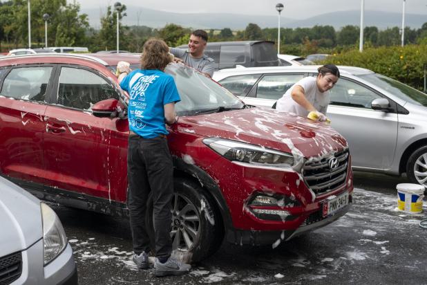 Volunteers cleaning a car for charity
